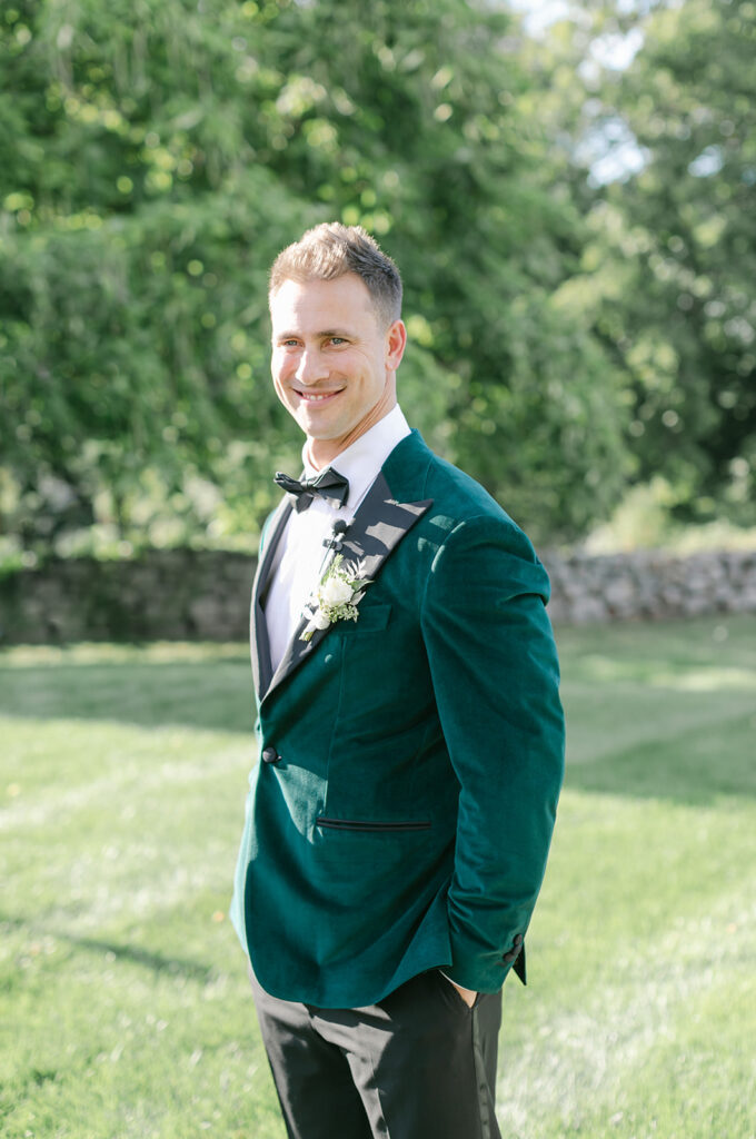 Groom in dark green tuxedo jacket smiling